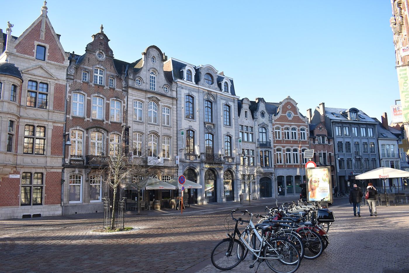 Rij geschilderde en bakstenen gevels aan de Grote Markt van Lier, met fietsen op de voorgrond
